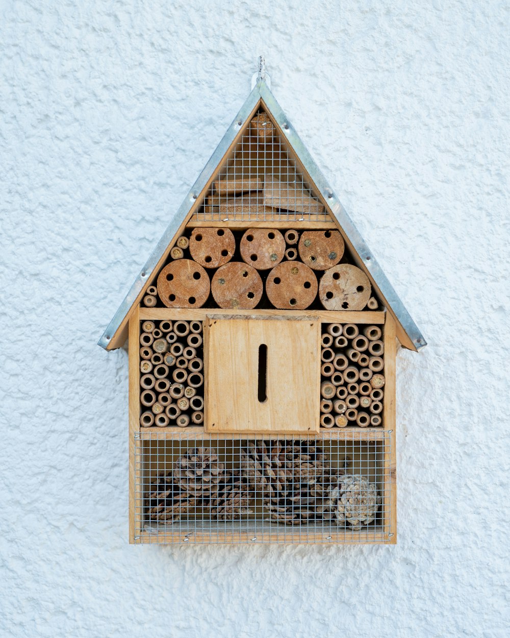 Braunes Vogelhaus aus Holz an weißer Wand