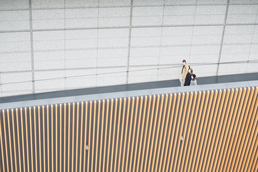 woman in black jacket and black pants standing beside brown wall