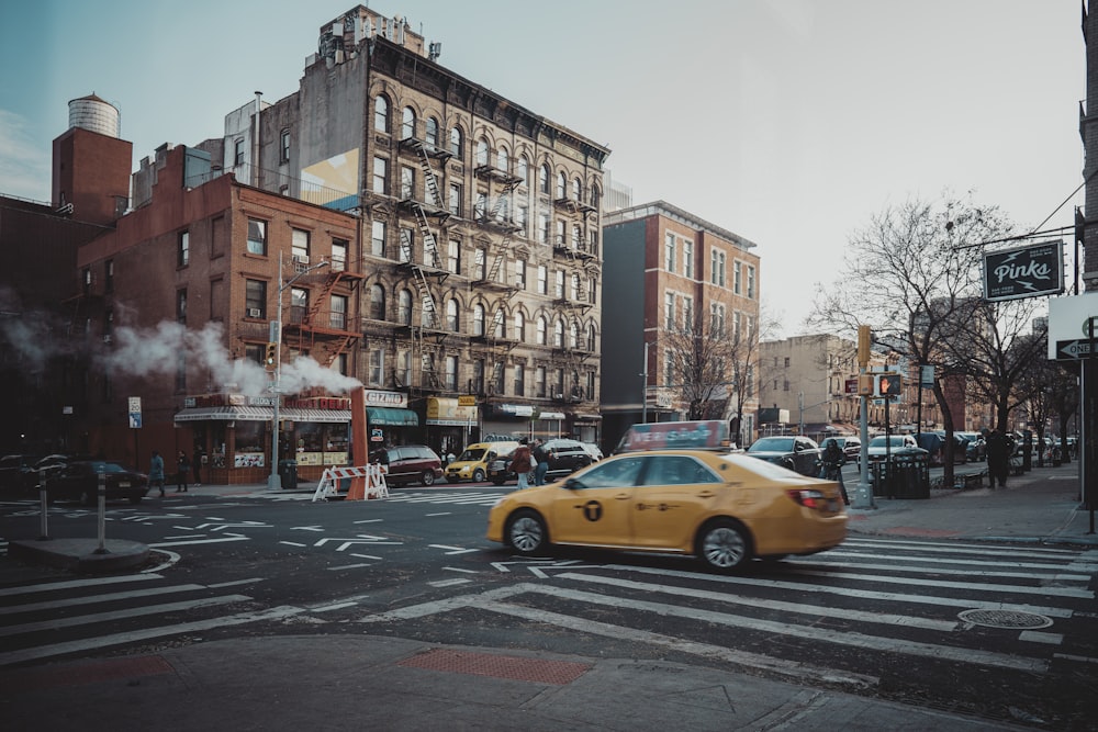 yellow taxi cab on road near building during daytime