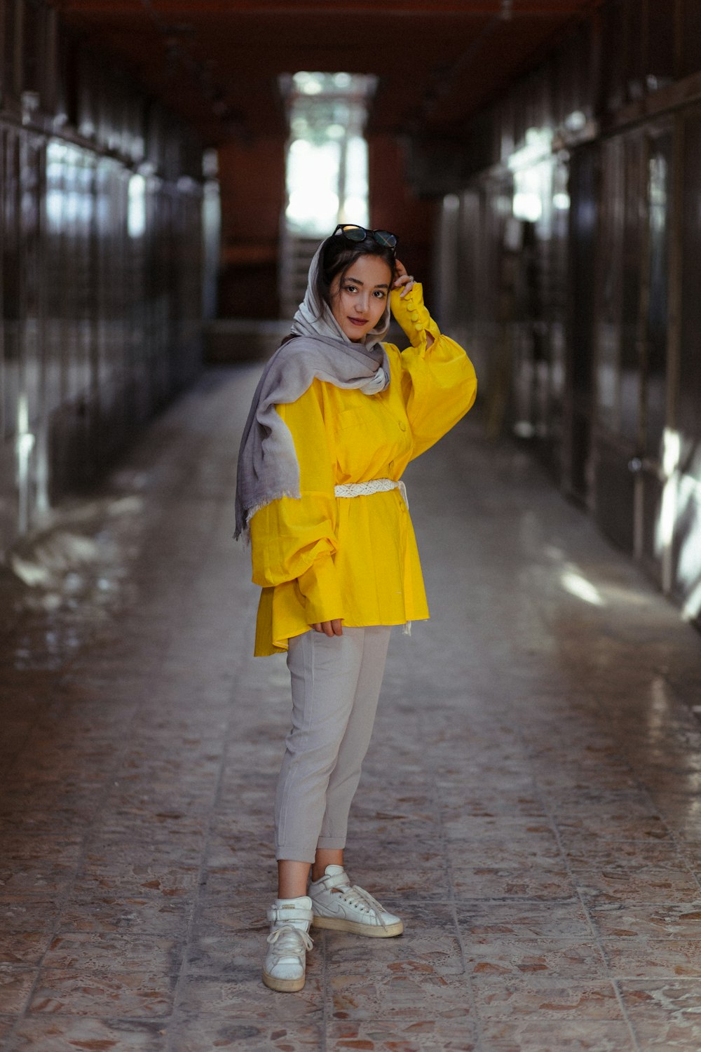 woman in yellow coat and white pants standing on sidewalk during daytime