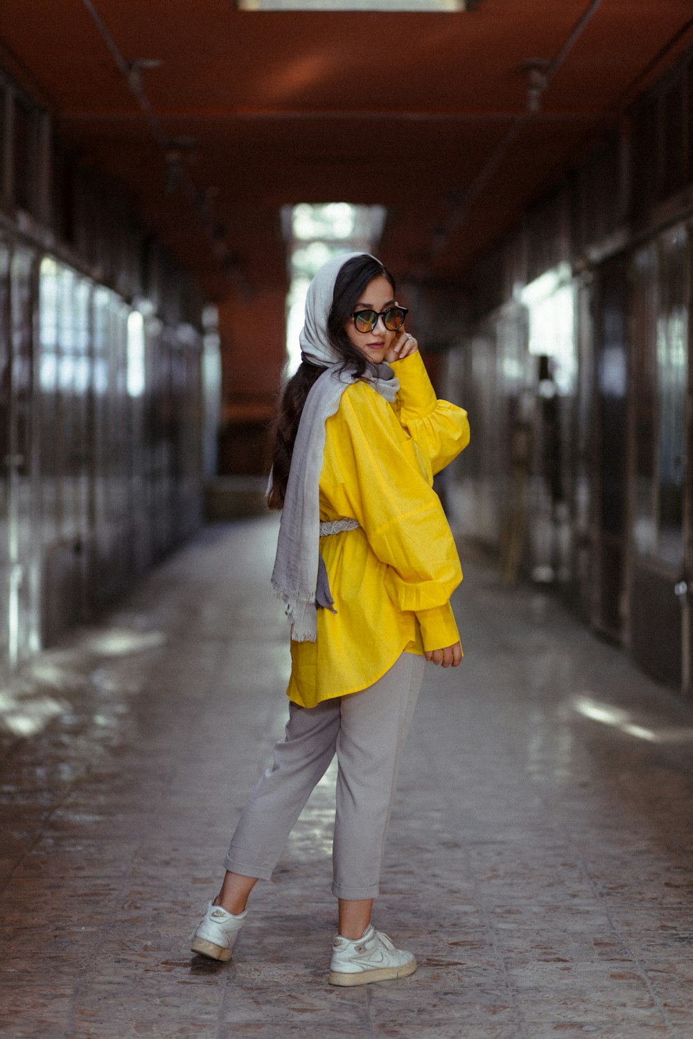 woman in yellow coat and black pants standing on sidewalk during daytime