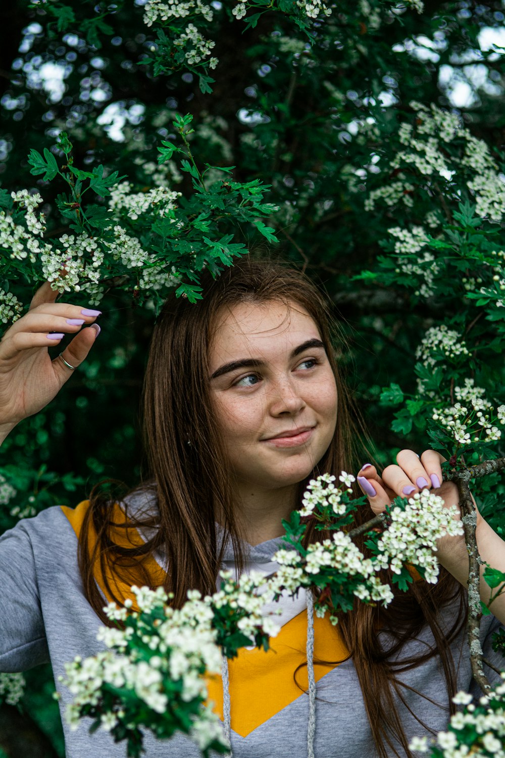 woman in gray shirt holding white flowers