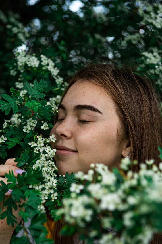 woman in white shirt smiling beside pink flowers