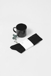 A stack of crisp, plain white socks arranged neatly beside a small plant.