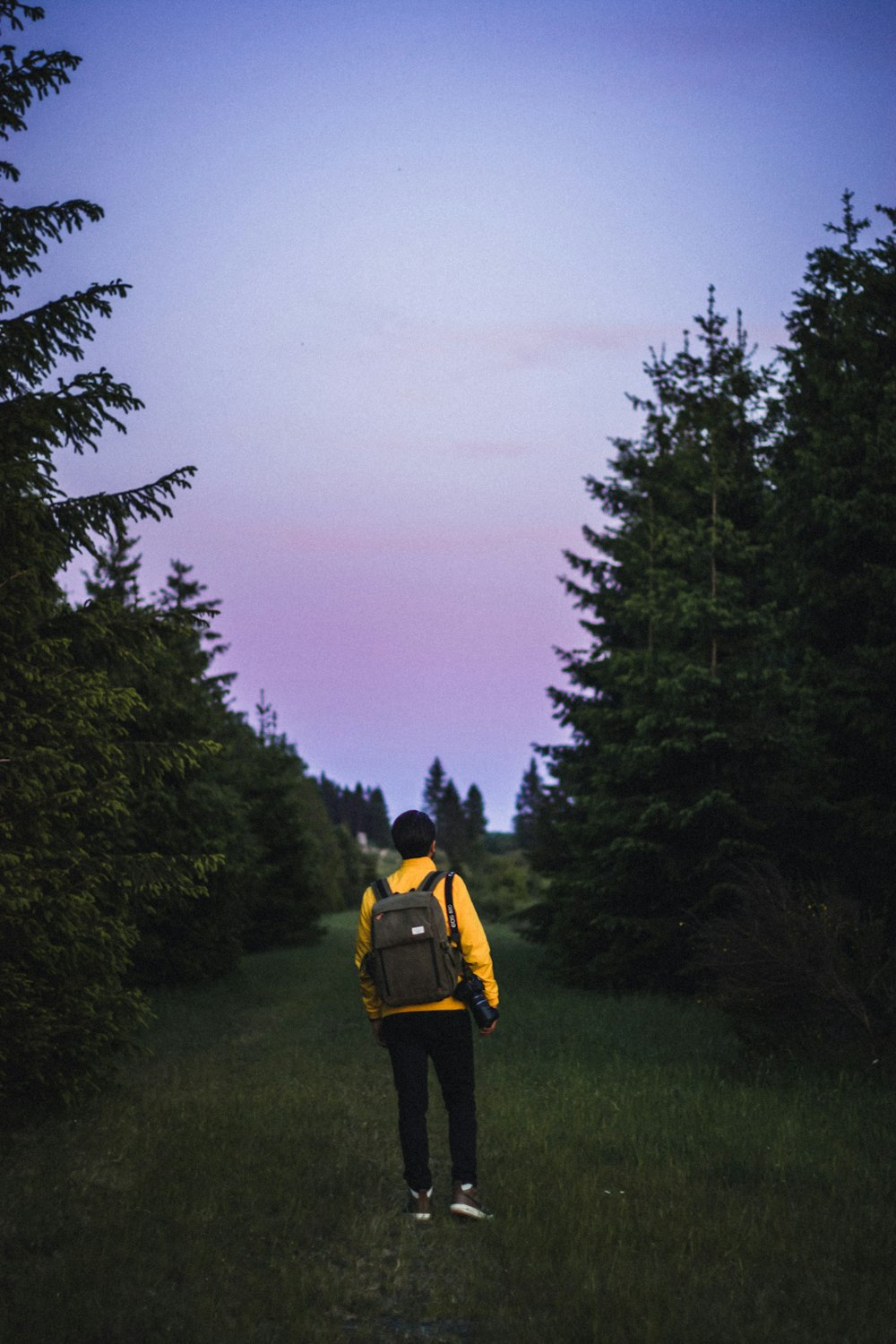 man in yellow jacket and black pants standing on green grass field