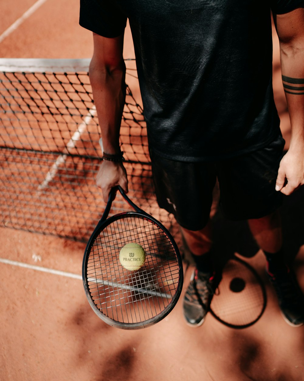 person in black shorts holding green tennis racket