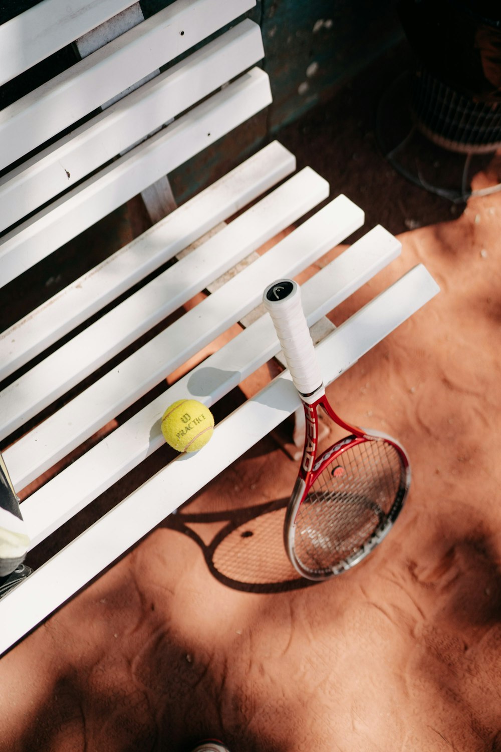 bola de tênis amarela no banco de madeira marrom