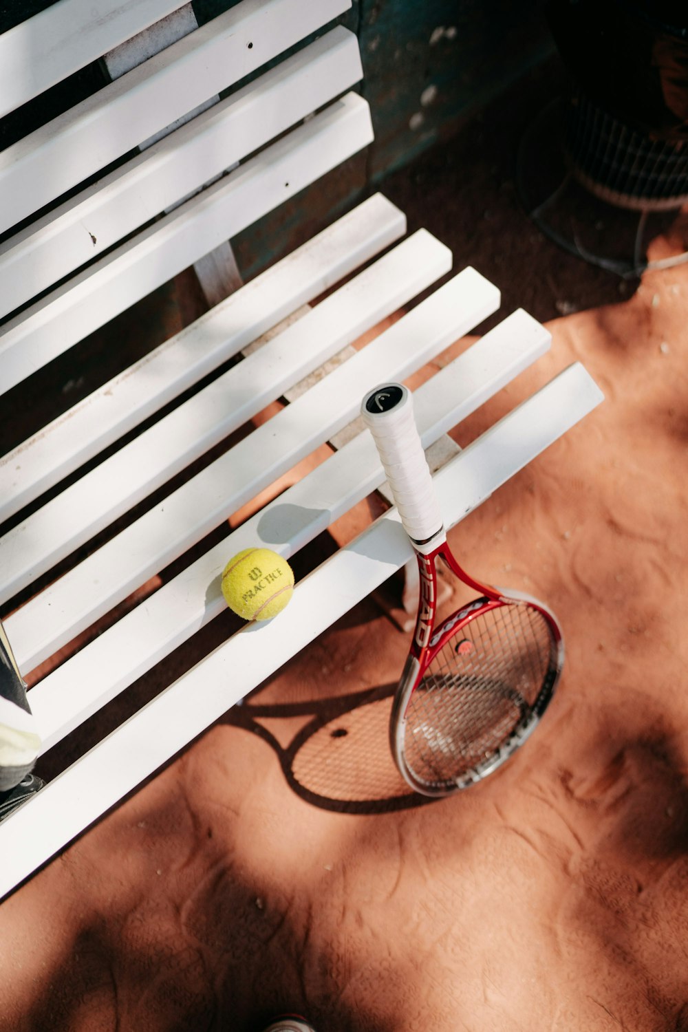 yellow tennis ball on brown wooden bench