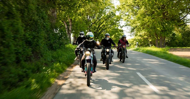 A cheerful group of friends enjoying a ride on two-wheelers along a coastal road.