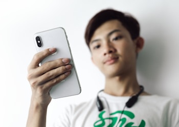 man in white crew neck shirt holding silver iphone 6