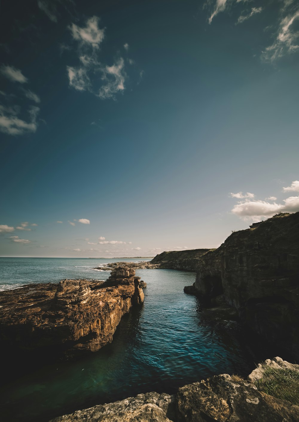 brown rocky mountain beside blue sea under blue sky during daytime