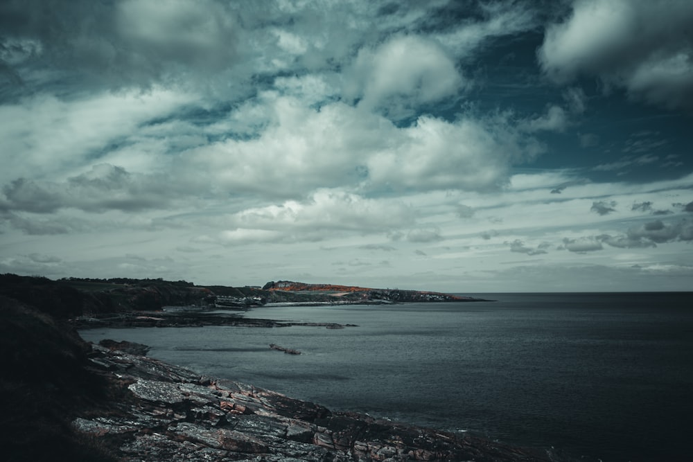 body of water under blue sky and white clouds during daytime