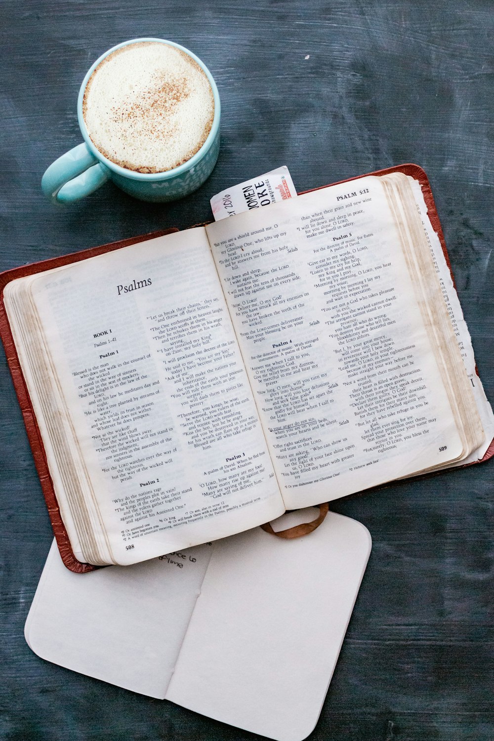 white book page beside white ceramic mug on brown wooden table