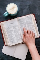 An open book on a desk with a cup of coffee beside it.