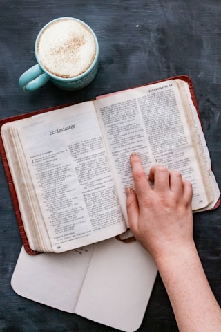 Open books on a wooden table with a cup of coffee.