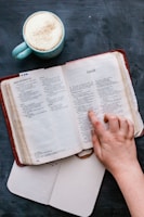 Close-up of an open book with highlighted passages and a cup of coffee nearby.