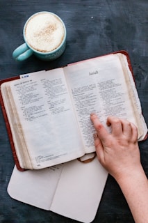 An open textbook with highlighted sections and a coffee cup beside it.