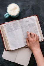 A close-up of hands turning pages of the Lifeshift Book, with a cup of tea nearby.