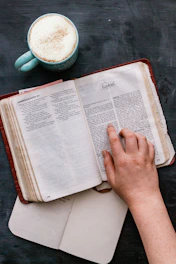 A cozy scene of a woman reading a beautifully designed Bible study workbook with a cup of tea nearby.