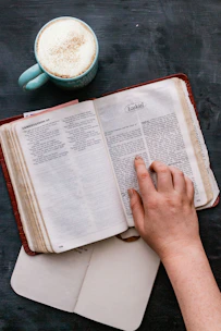 A cozy scene of a woman reading a beautifully designed Bible study workbook with a cup of tea nearby.