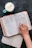 Close-up of hands flipping through the Infinite Zoe paperback devotional with a cup of tea nearby.