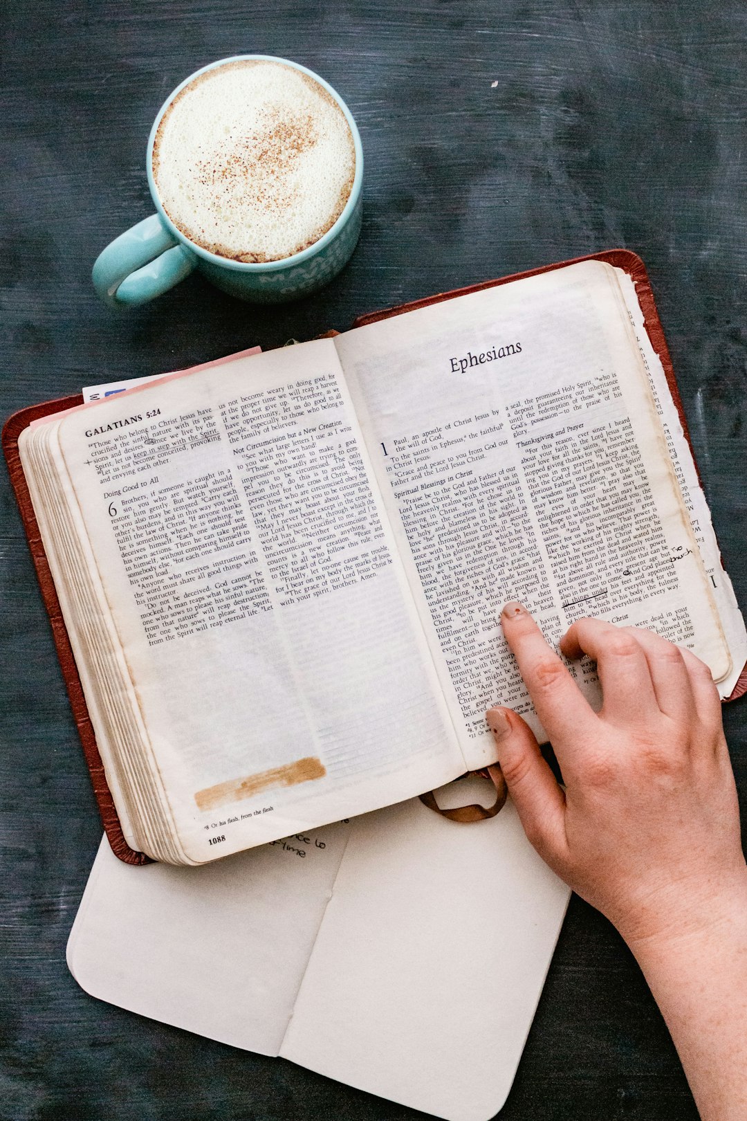 person holding book page near white ceramic bowl