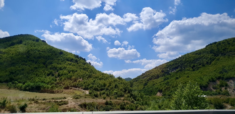 green mountains under blue sky and white clouds during daytime