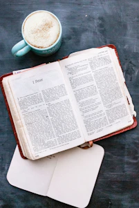 A cozy study corner with an open Bible, a notebook, and a steaming cup of tea beside a calendar marked with Bible study events.