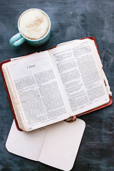 A cozy study corner with an open Bible, a notebook, and a steaming cup of tea beside a calendar marked with Bible study events.