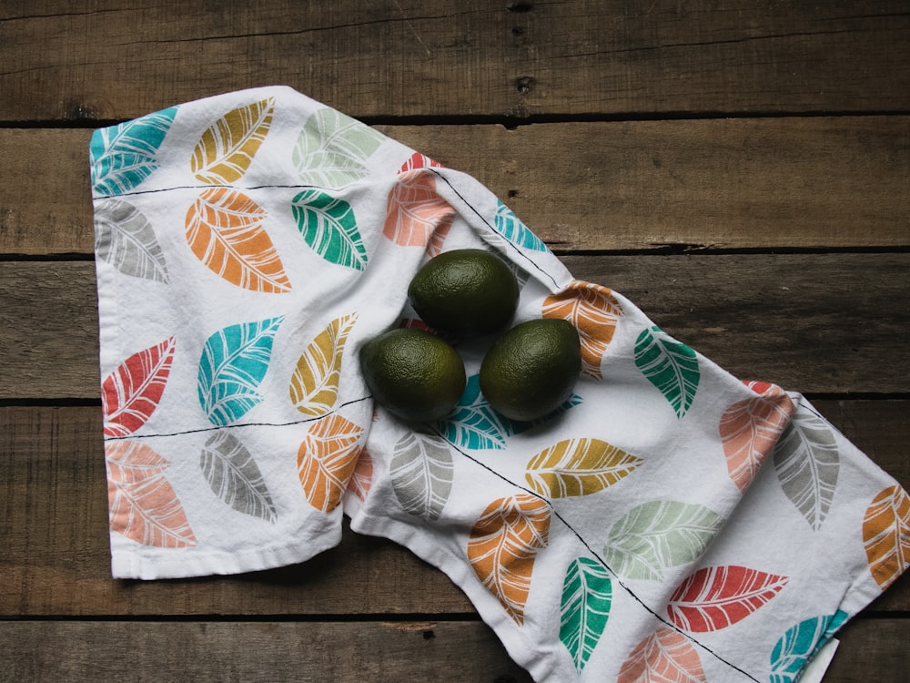 green round fruits on white and orange floral textile
