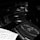 A close-up of an interior section of a piano, focusing on the strings and an engraved plate reading 'Steinway & Sons, New York Hamburg'. A sheet of music is partially visible in the foreground. The image is in black and white, highlighting the textures and metal components.
