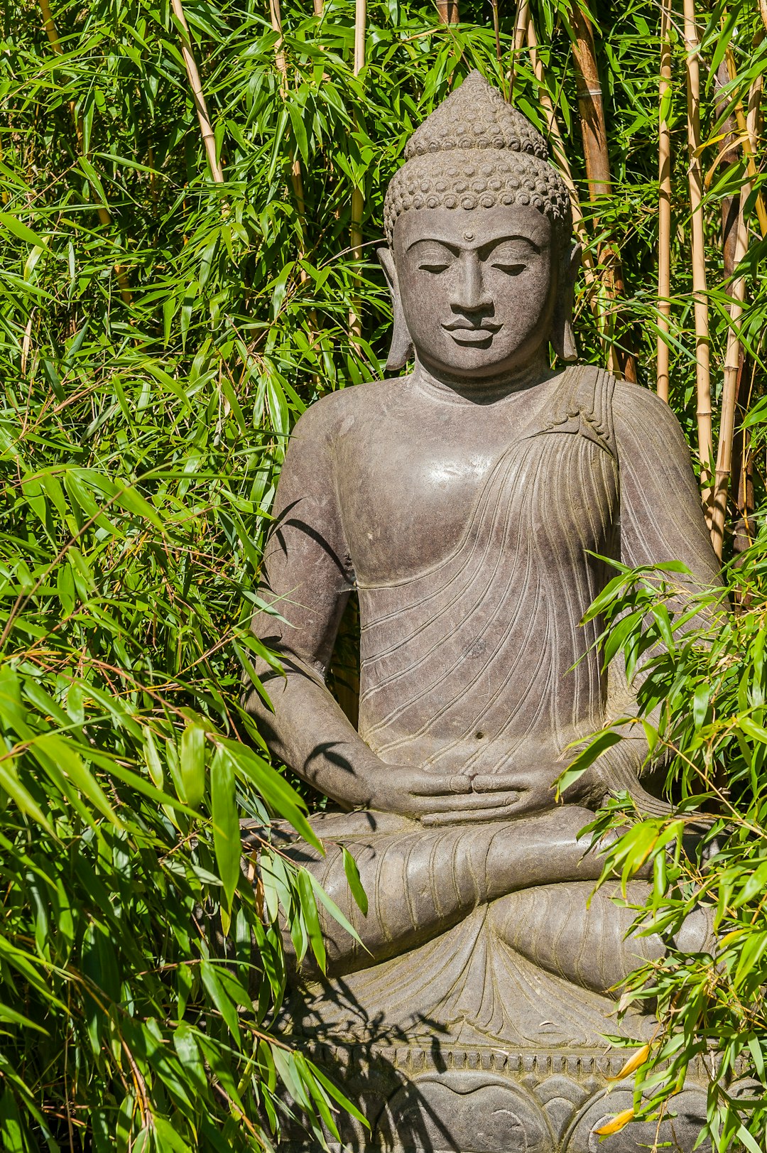gray concrete statue surrounded by green plants
