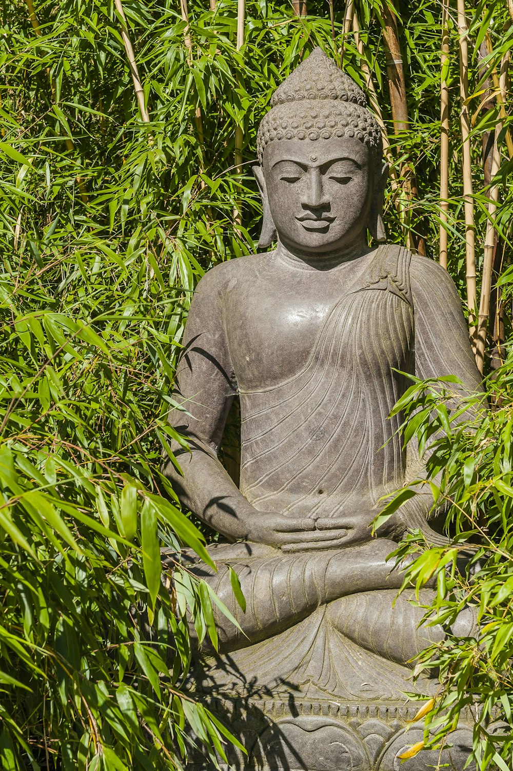 gray concrete statue surrounded by green plants