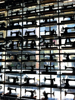 A row of used sewing machines in various brands and models displayed on shelves.