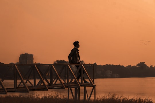 silhouette of man standing on wooden dock during sunset in Kota India