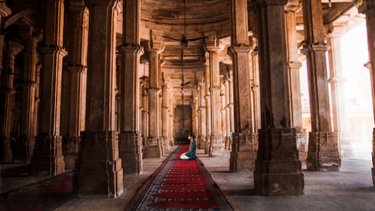 person in red and black dress sitting on red carpet in Ajmer India