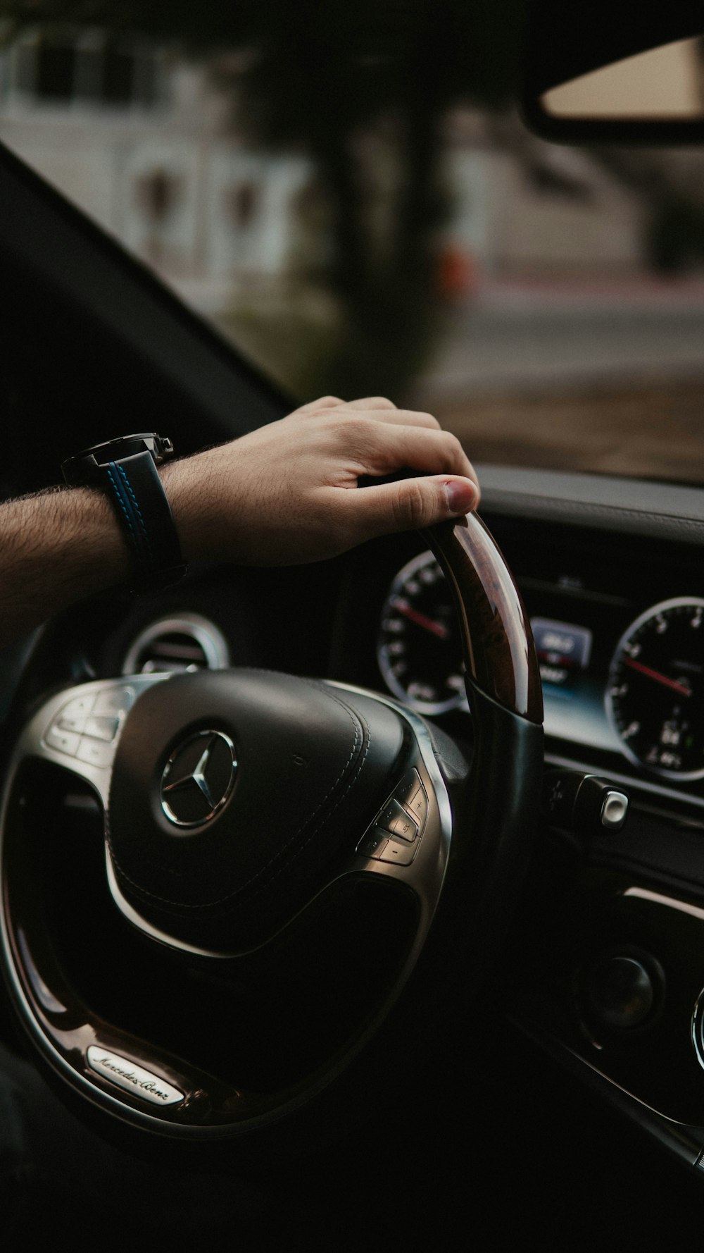 person wearing black smart watch holding black mercedes benz steering wheel