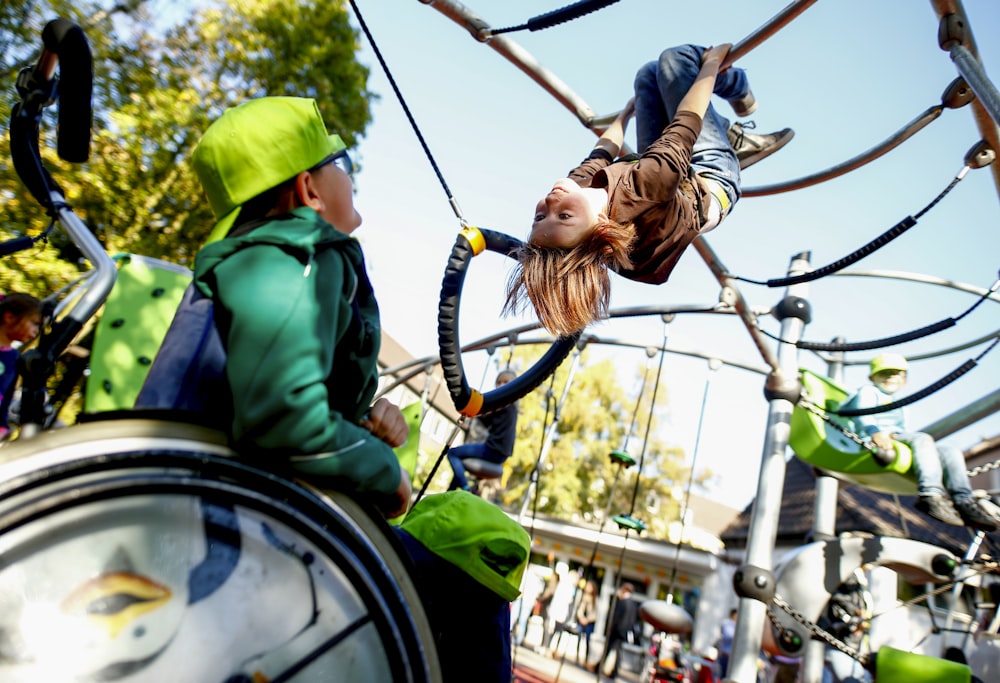 man in green jacket and brown pants riding on white and black swing during daytime