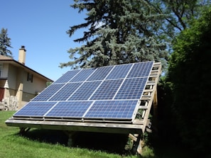 A sunny ground-mounted solar panel array with sturdy structural supports anchored.