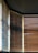 Vertical blinds partially open, allowing light to filter through, creating a pattern of light and shadow on the wooden slats. A mix of warm and cool tones is visible, with contrasting shades on each side influenced by the angle of the light.