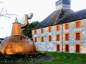 Close-up of a distiller carefully inspecting a copper still in a rustic distillery.