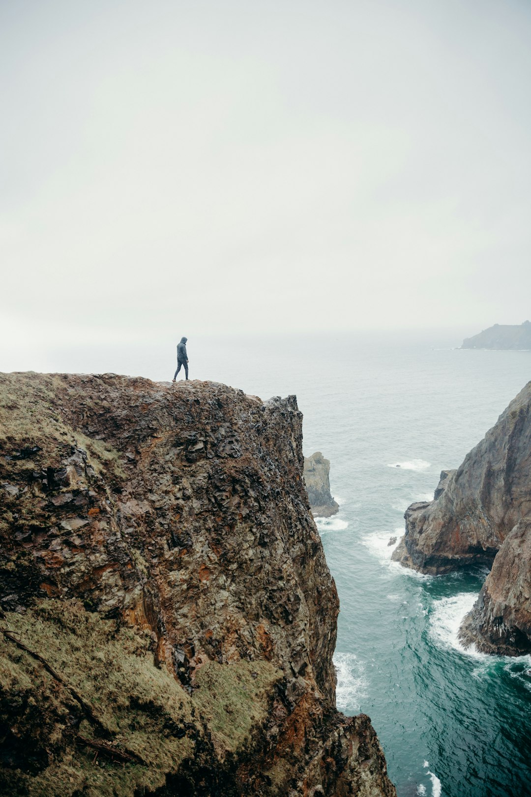 person standing on rock formation near body of water during daytime