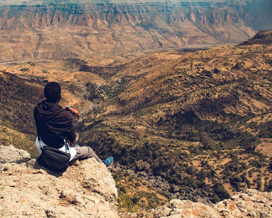 man in black hoodie sitting on rock formation looking at the grand canyon in Debre Libanos Ethiopia