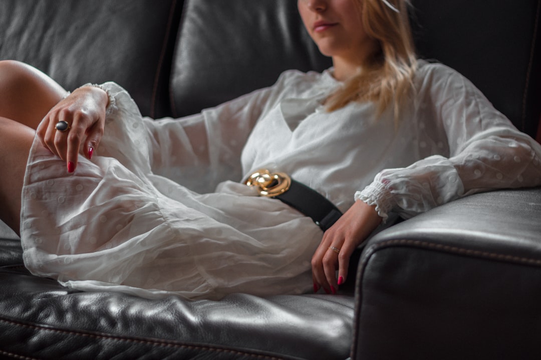 woman in white long sleeve shirt sitting on black leather couch