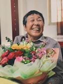 A joyful recipient holding a colorful bouquet at home.