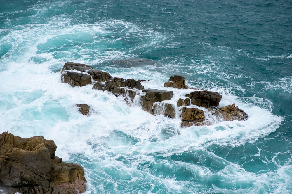 costa rochosa marrom com ondas do oceano durante o dia