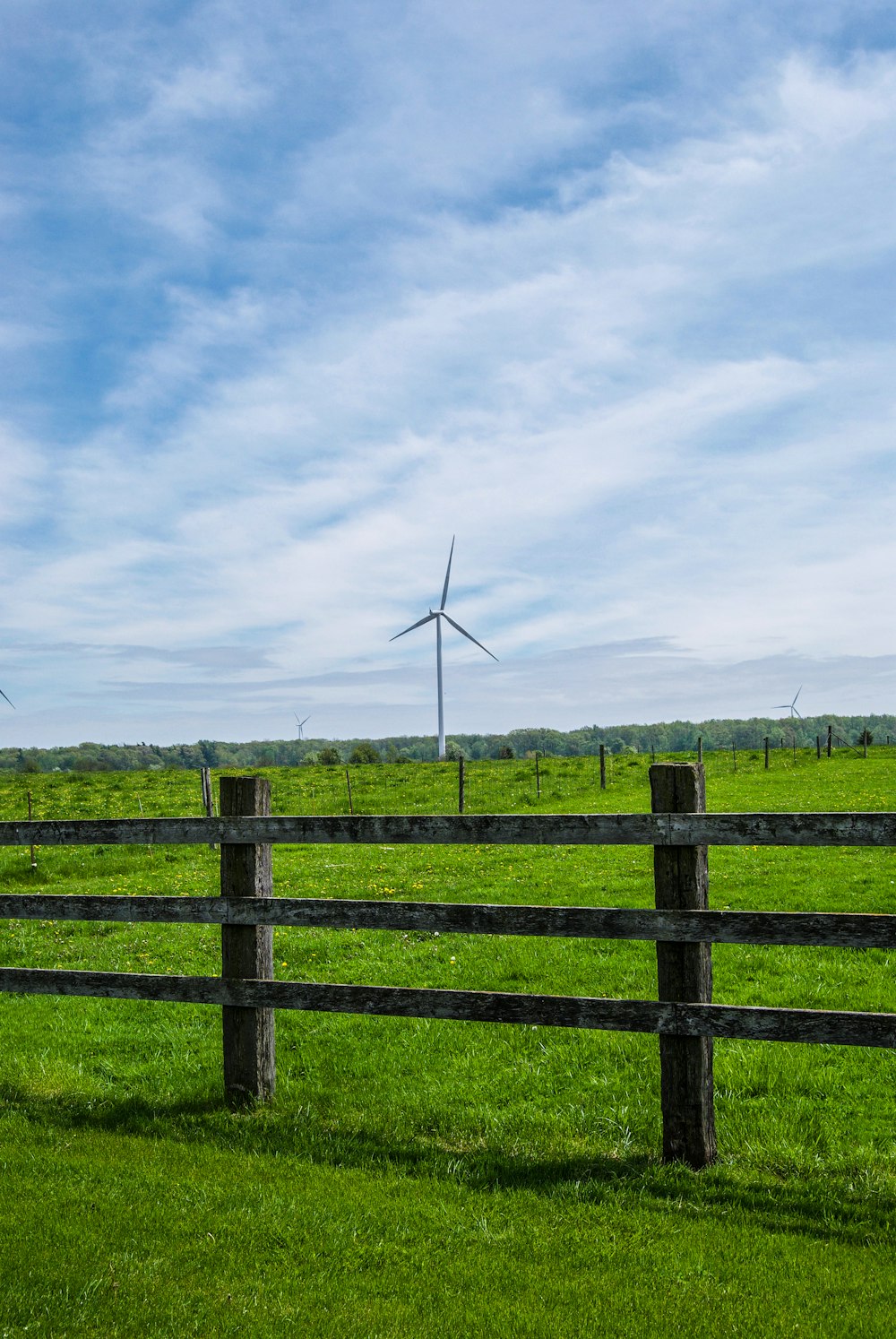 wind turbines on green grass field under white clouds and blue sky during daytime