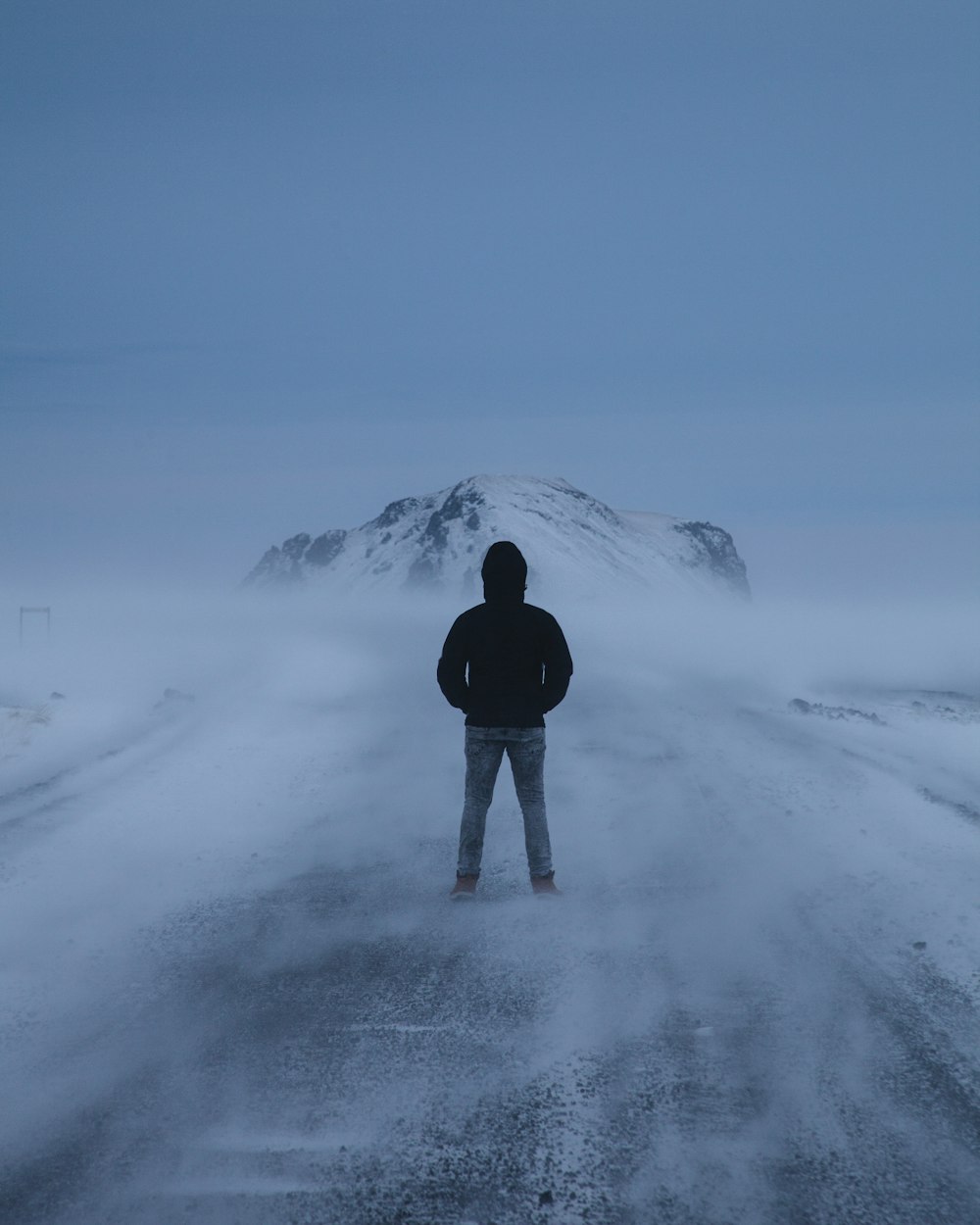 person in black jacket standing on snow covered ground during daytime