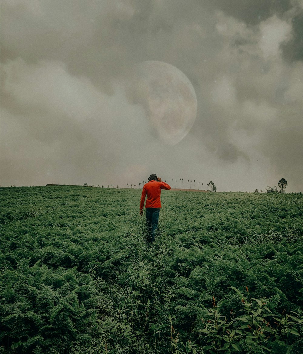 man in red jacket standing on green grass field during daytime