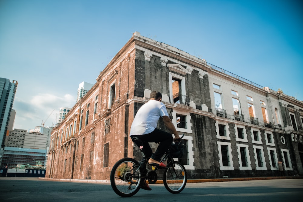 man in white shirt riding on black bicycle on road during daytime